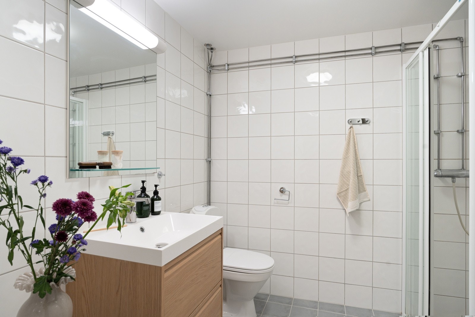 Veggmontert servantskap med heldekkende vask og ett-greps armatur i krom. Gulvstående klosett og opplegg for vaskemaskin. Galleribilde