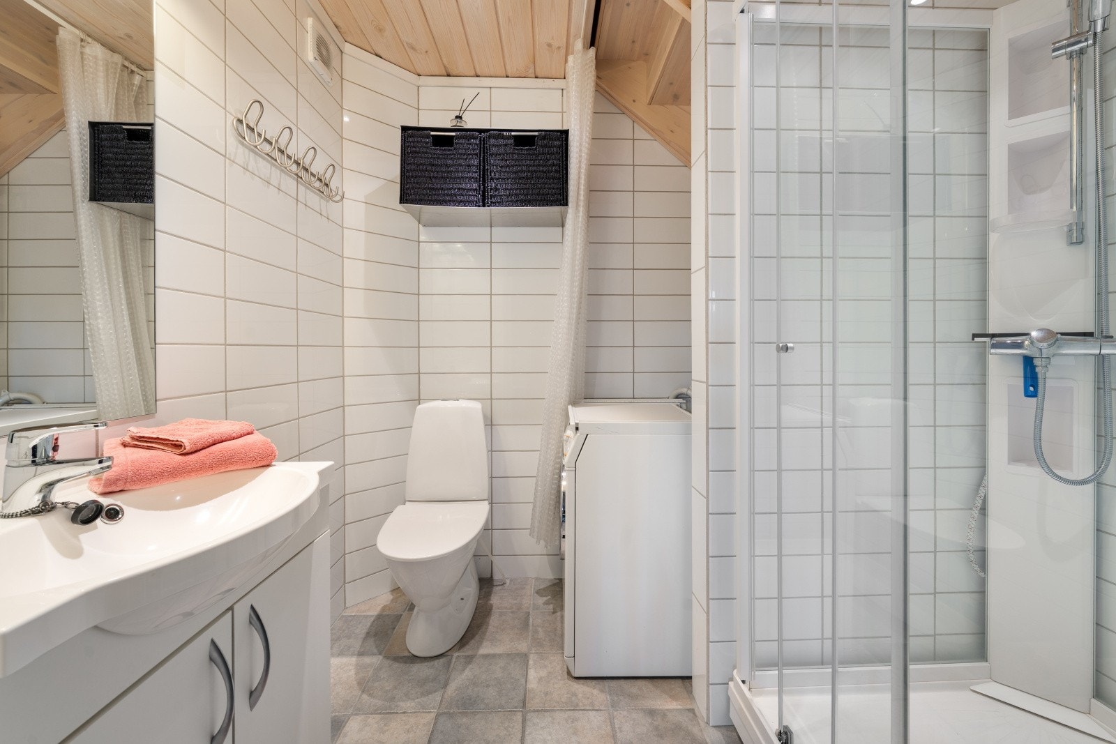 Flislagt bad med varme i gulv. Badet har dusjkabinett, toalett, servant med underskap samt opplegg til vaskemaskin. Galleribilde