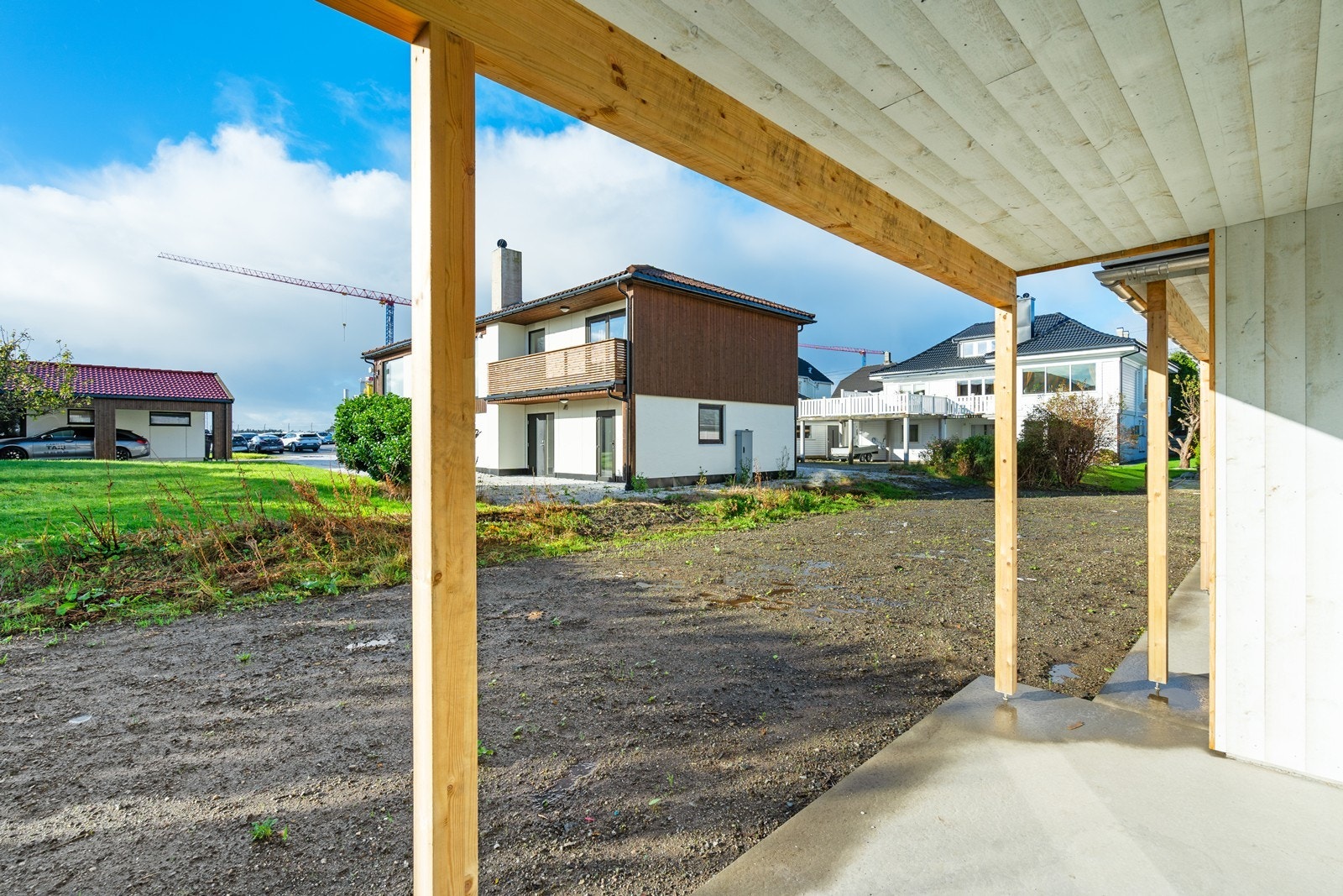 Vestvendt og overbygget betongplatting med utgang til hage med boltreplass til utelek og trampoline Galleribilde