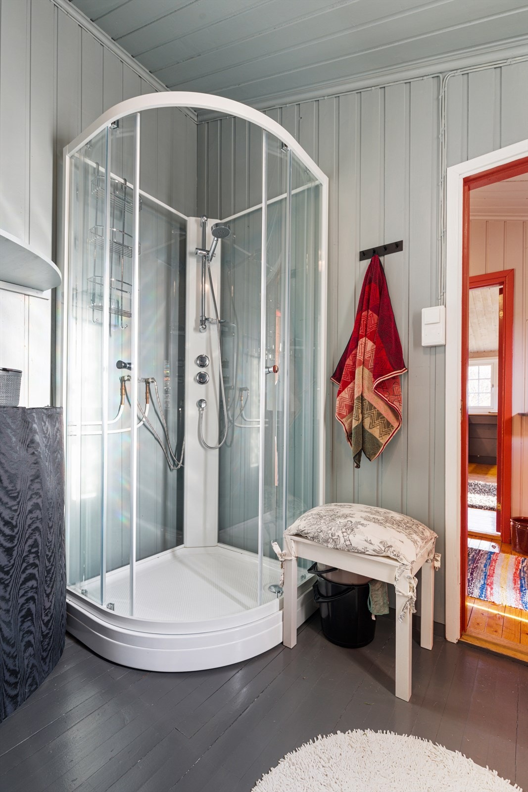 Badet har malte gulvbord og malt panel på vegger og i tak | rommet er utstyrt med baderomsinnredning, dusjkabinett og wc Galleribilde