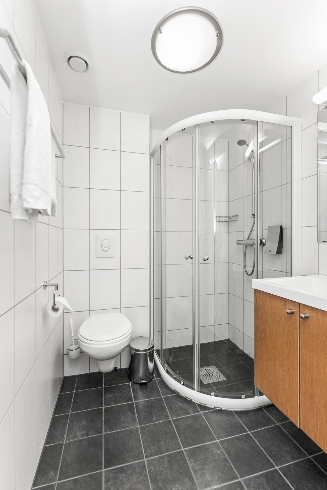 Bad til hotellrom har dusjhjørne, vegghengt toalett og innredning med nedfelt servant. Her er varmekabler i gulv. Galleribilde