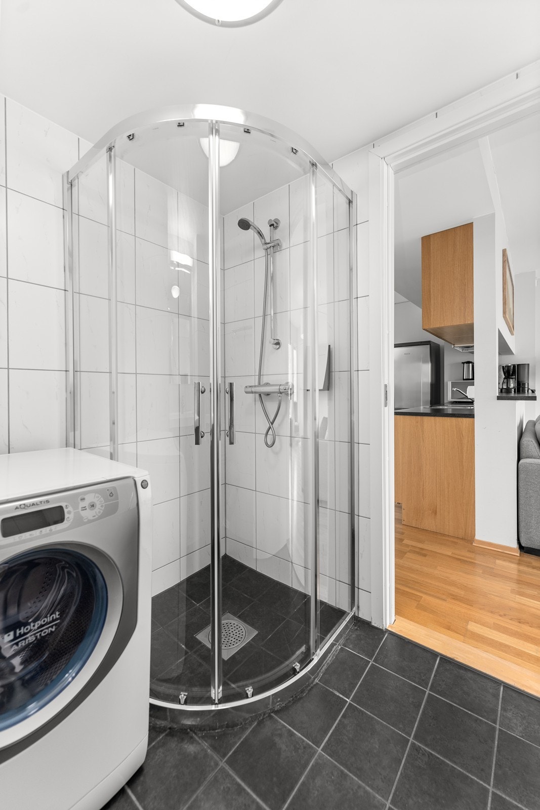 Bad til leiligheten. Her er det dusjhjørne, opplegg til vaskemaskin, vegghengt toalett og innredning med nedfelt servant. Galleribilde