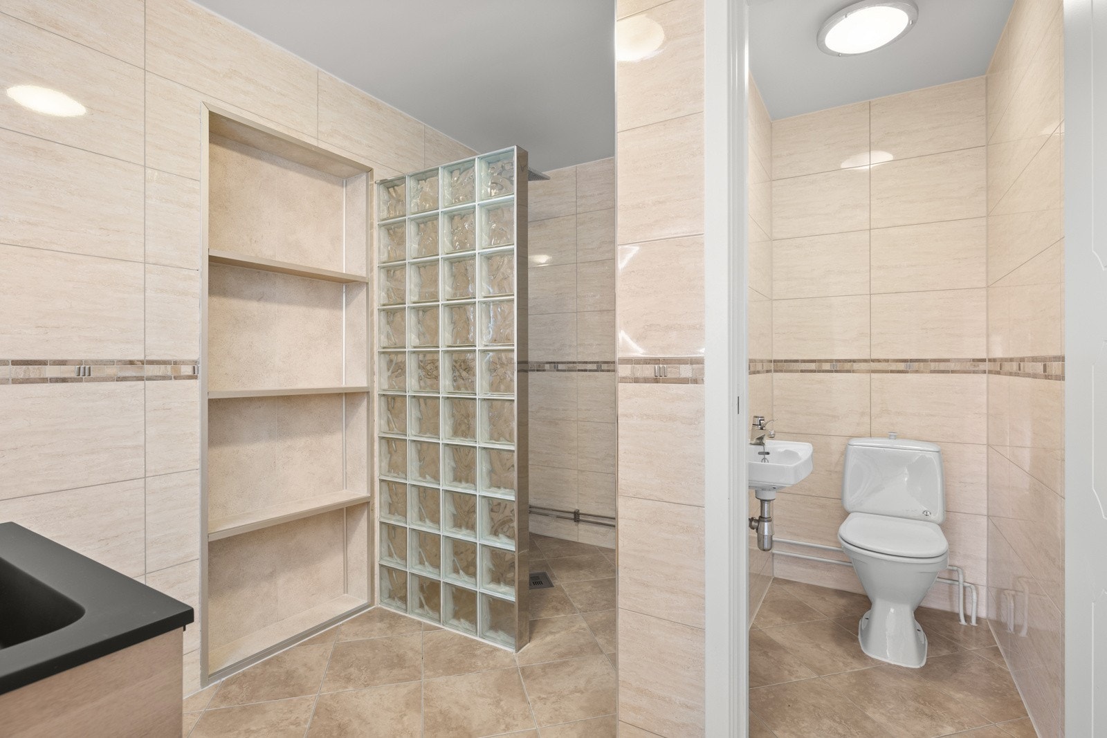 Badet er utstyrt med servantinnredning med skuffer og sort servant med tilhørende ettgrepskran, begge nytt fra 2025. Galleribilde