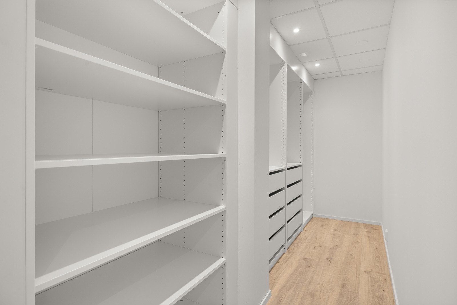 Tilhørende romslig garderobeløsning med god oppbevaringsplass i hyller og skuffer gir svært praktiske lagringsmuligheter. Galleribilde