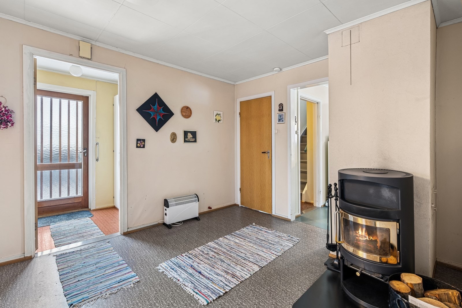 Fra entreen kommer du inn i boligen, og her finner du en peisovn som gir god varme på kalde dager. Galleribilde