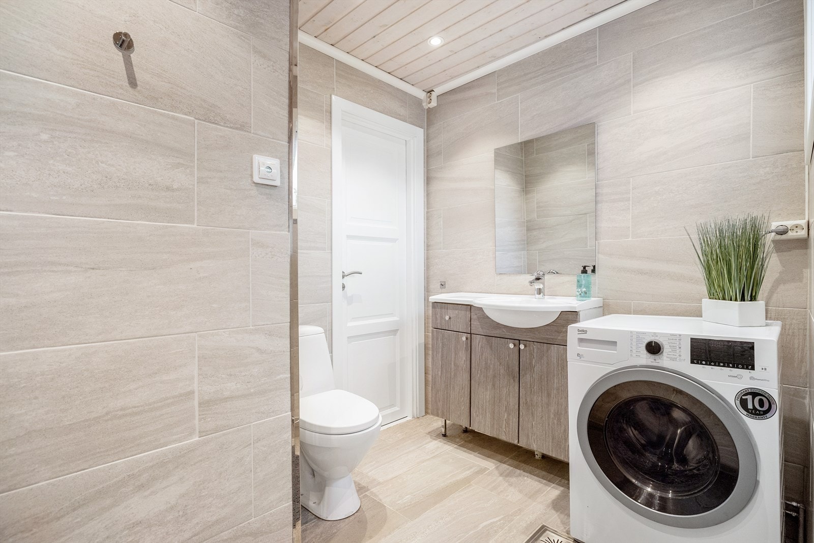 Pent flislagt bad med varmekabler i gulv. Badet er utstyrt med servant over innredning, toalett og dusjhjørne Galleribilde