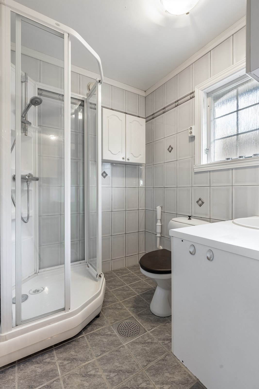 Pent og funksjonelt bad med dusjkabinett, servant og toalett Galleribilde