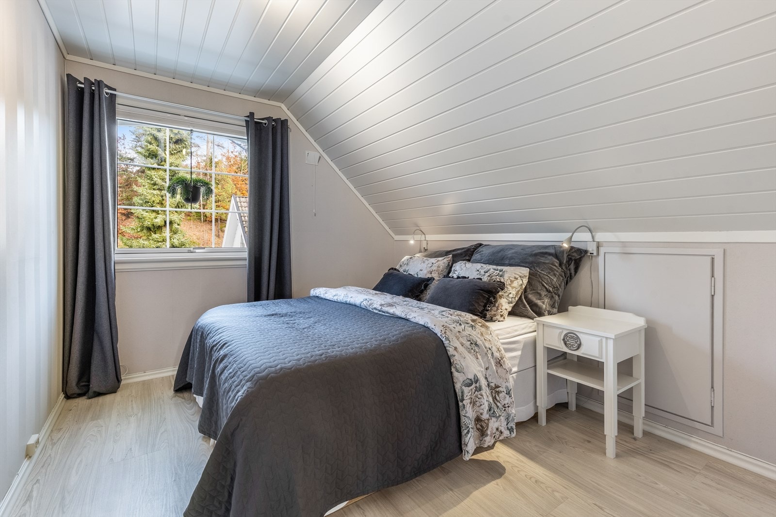 Behagelig soverom med praktisk oppbevaring, lune fargetoner og utsyn mot naturen Galleribilde