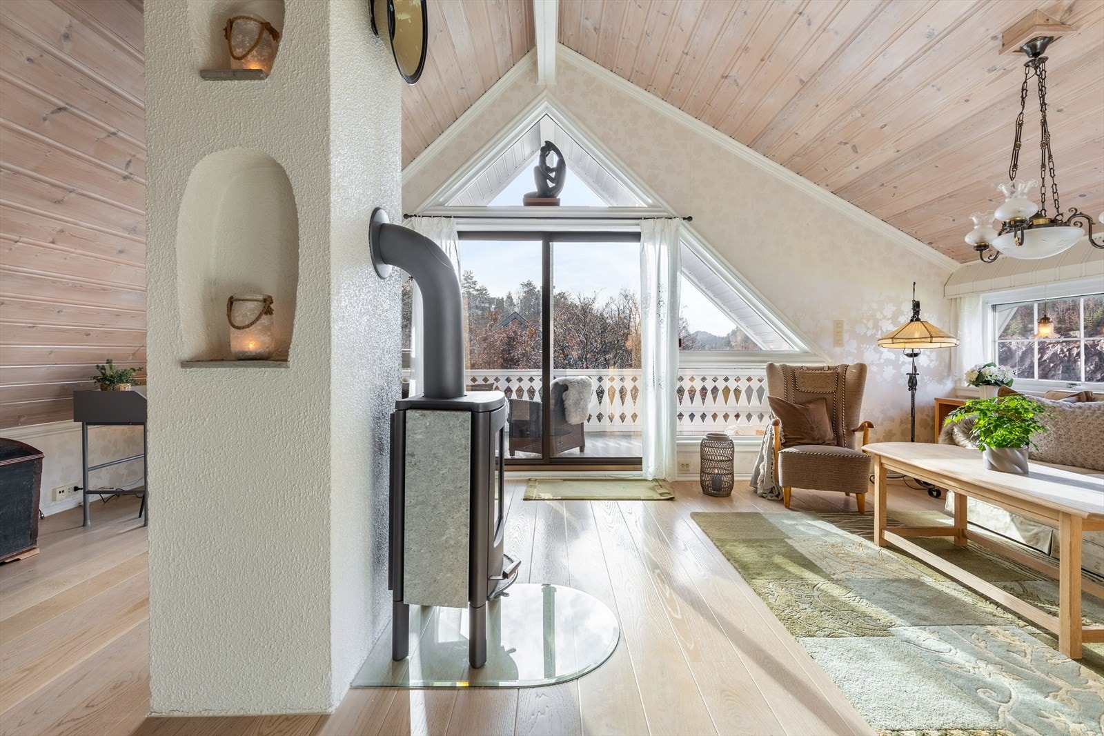 Peisovn og skrå himling skaper en lun og sjarmerende atmosfære på loftet Galleribilde
