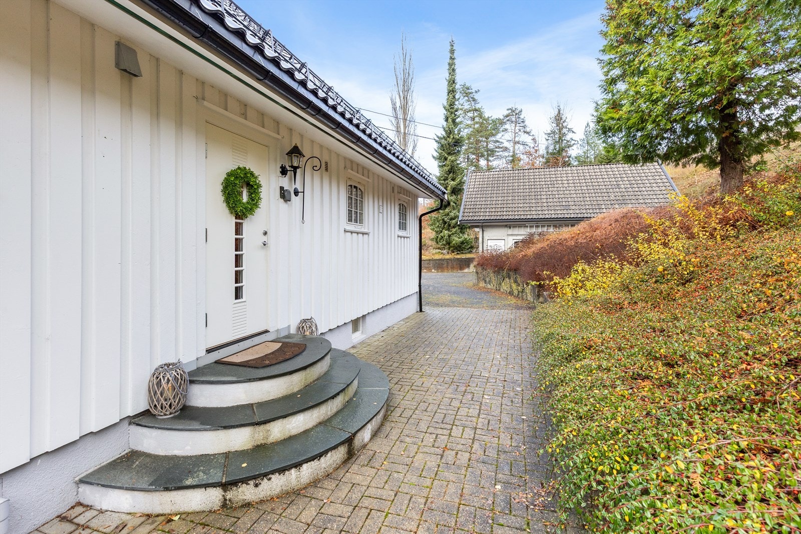 Pent inngangsparti og steinlagt gårdsplass med kort vei til garasje Galleribilde