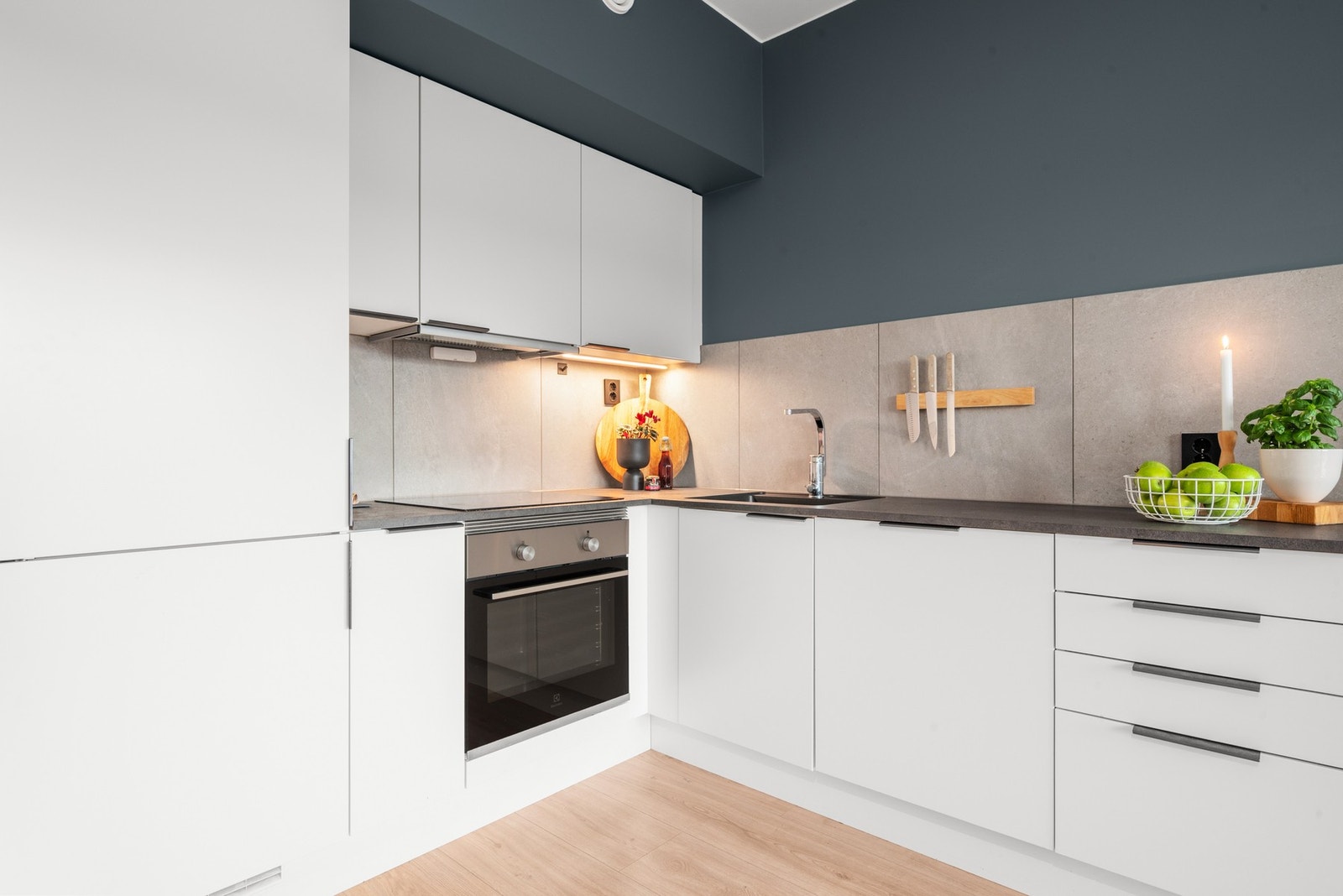 Tidløst kjøkken med integrerte hvitevarer. Eier har gjort tilpasninger som blant annet sort, underlimt vask og fliser over benk. Galleribilde