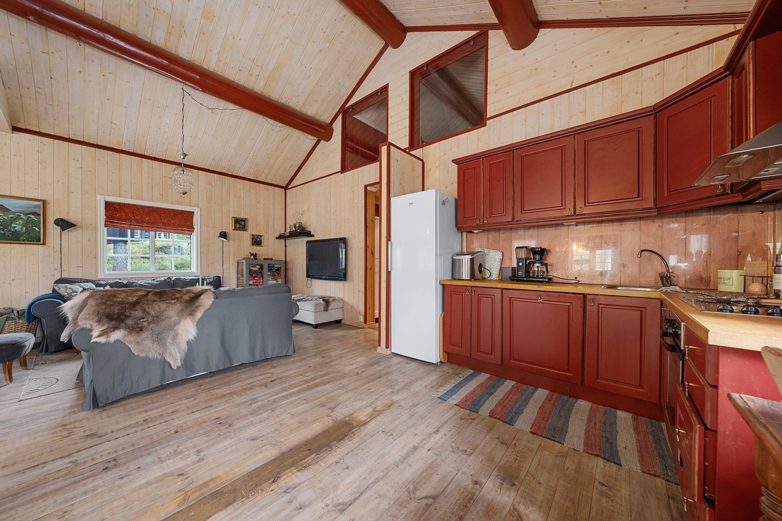 Kjøkkeninnredningen har rødmalte fronter og heltre benkeplate. Galleribilde