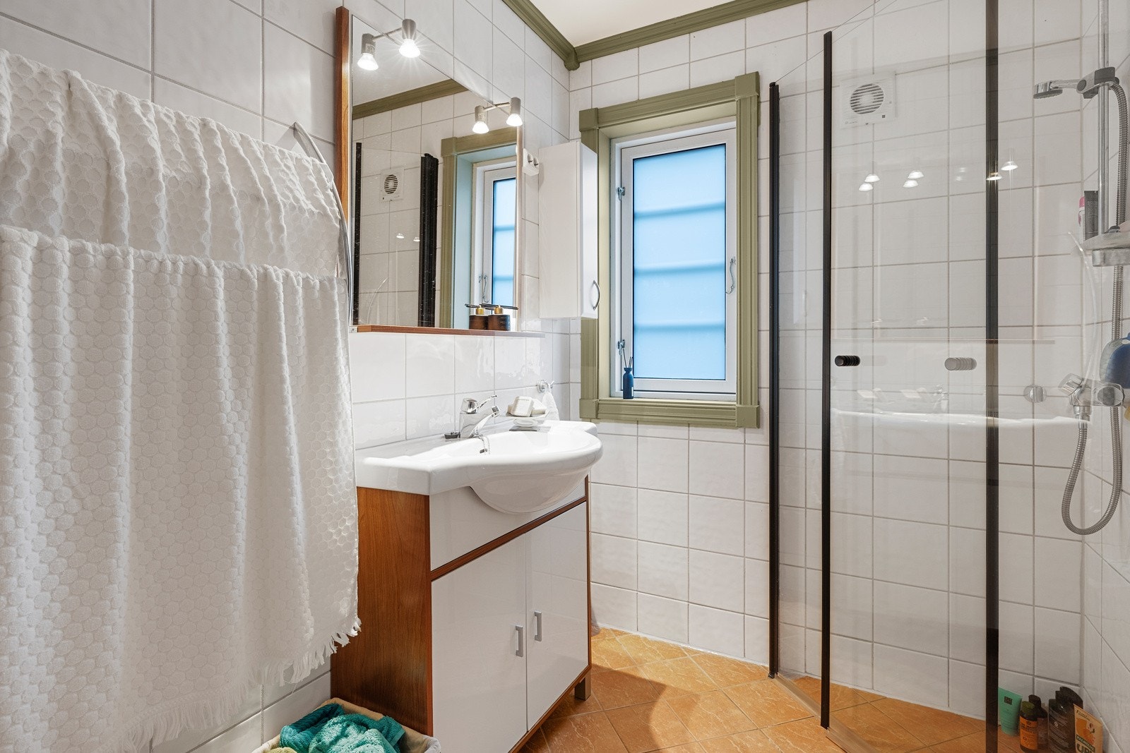 Badet er innredet med toalett, dusjhjørne med glassvegger og baderomsinnredning med servant. Galleribilde