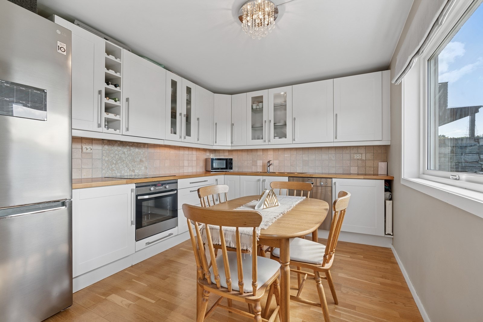 Kjøkkenet er innredet med hvite, profilerte fronter og benkeplate i tre. Galleribilde