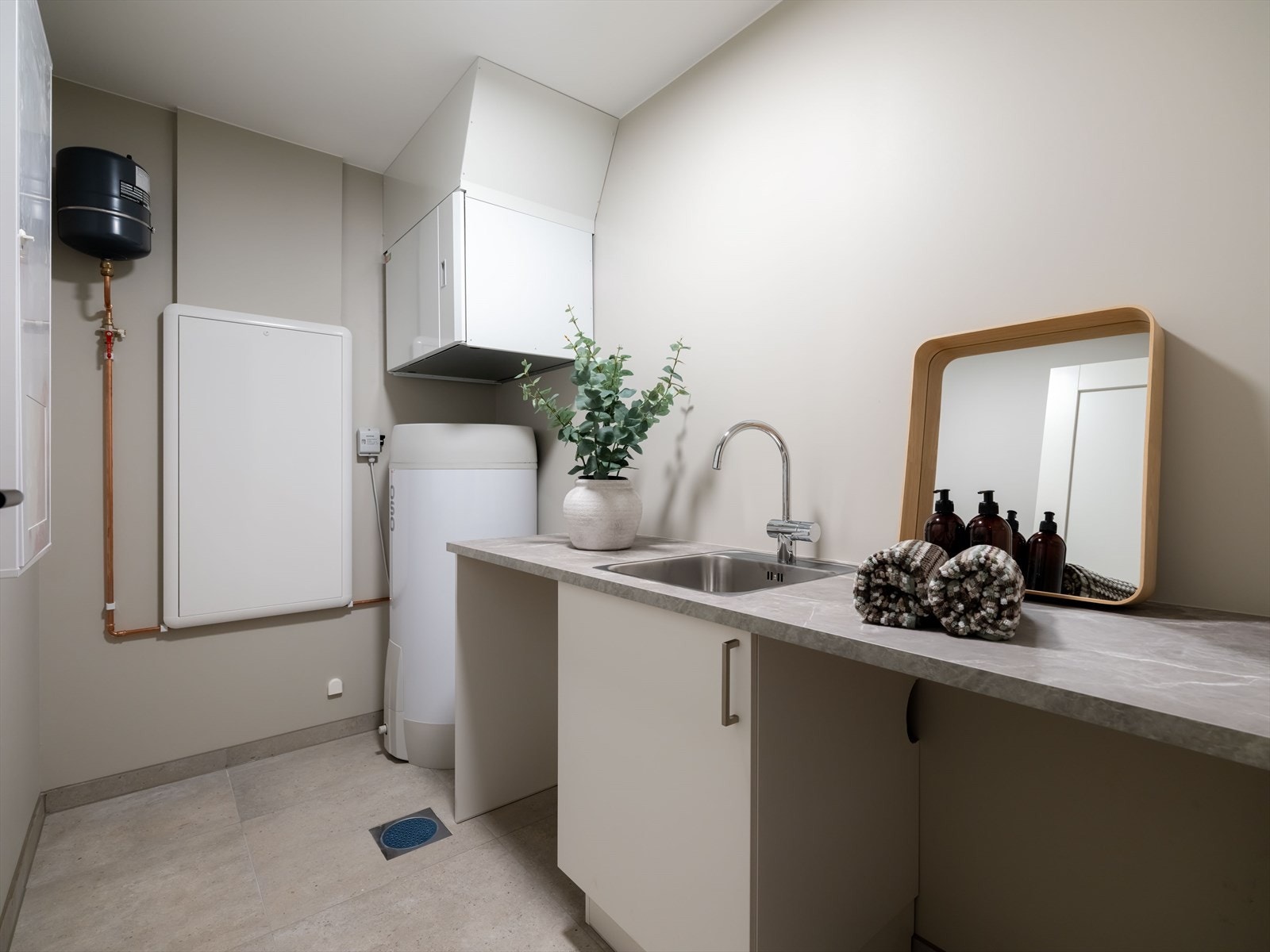 Separat vaskerom/teknisk rom i underetasjen med vaskeromsinnredning med utslagsvask og skap. Galleribilde