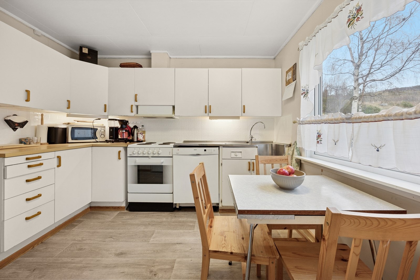 Kjøkkenet har innredning med slette hvite fronter og laminat benkeplate. Galleribilde