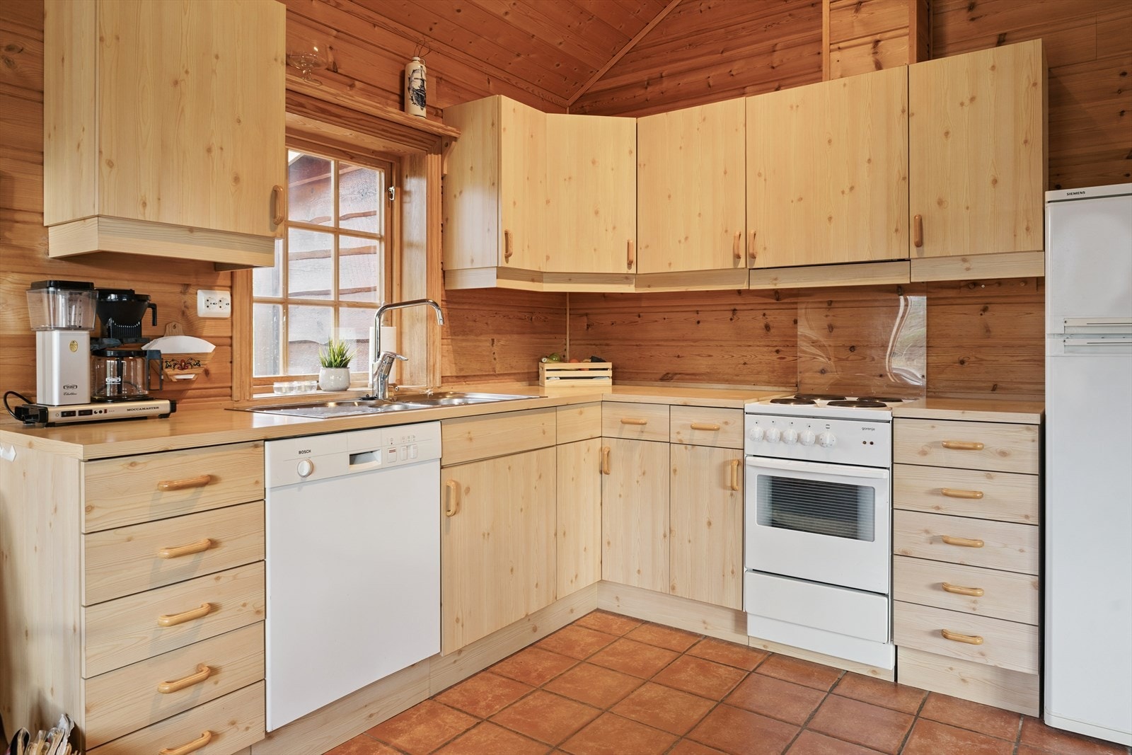 Kjøkkenkrok med innreiing frå byggeår. Her er det godt med plass for det du treng på hytta. Frittståande kvitevarer som komfyr, kjøleskap og oppvaskemaskin. Galleribilde