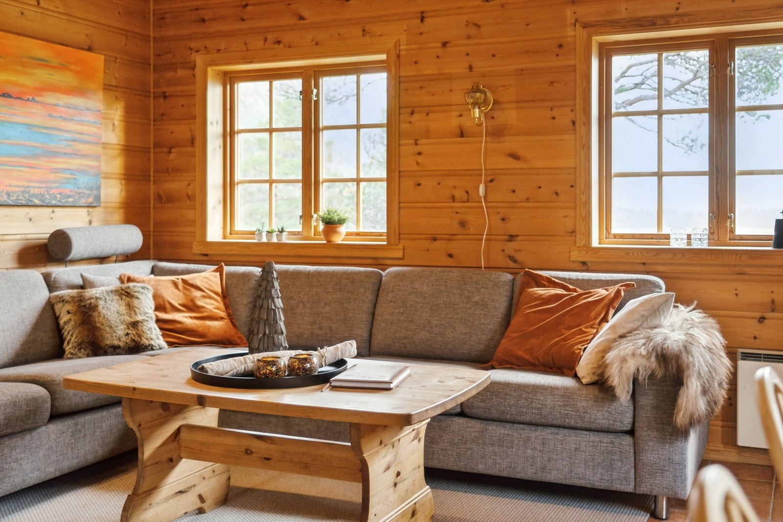Du har ei romsleg stove med panel på veggar og fleire vindaugsflater mot den nydelige naturen utom Galleribilde