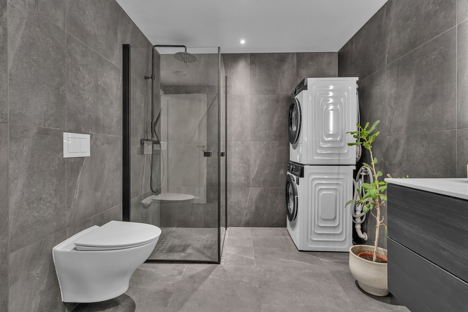 Badet er innredet med vegghengt toalett, dusjhjørne, servant m/underskuffer og opplegg til vaskemaskin Galleribilde