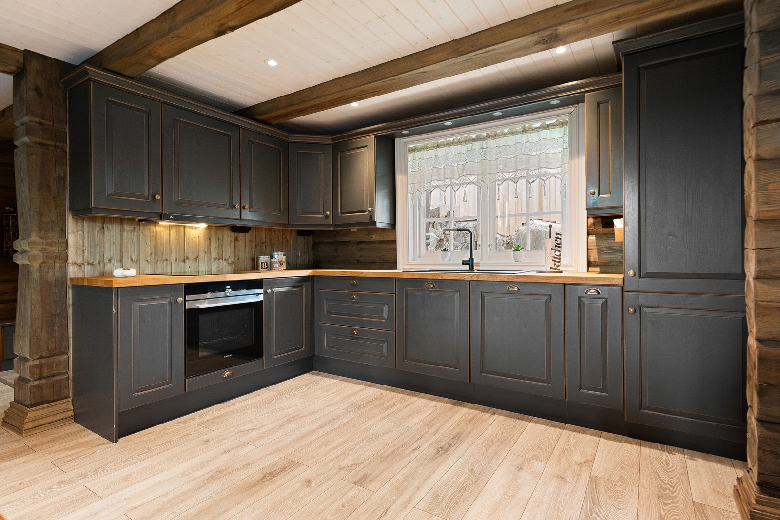 Kjøkkenet har en innredning i tradisjonell hyttestil med mørke, profilerte fronter og integrerte hvitevarer. Galleribilde