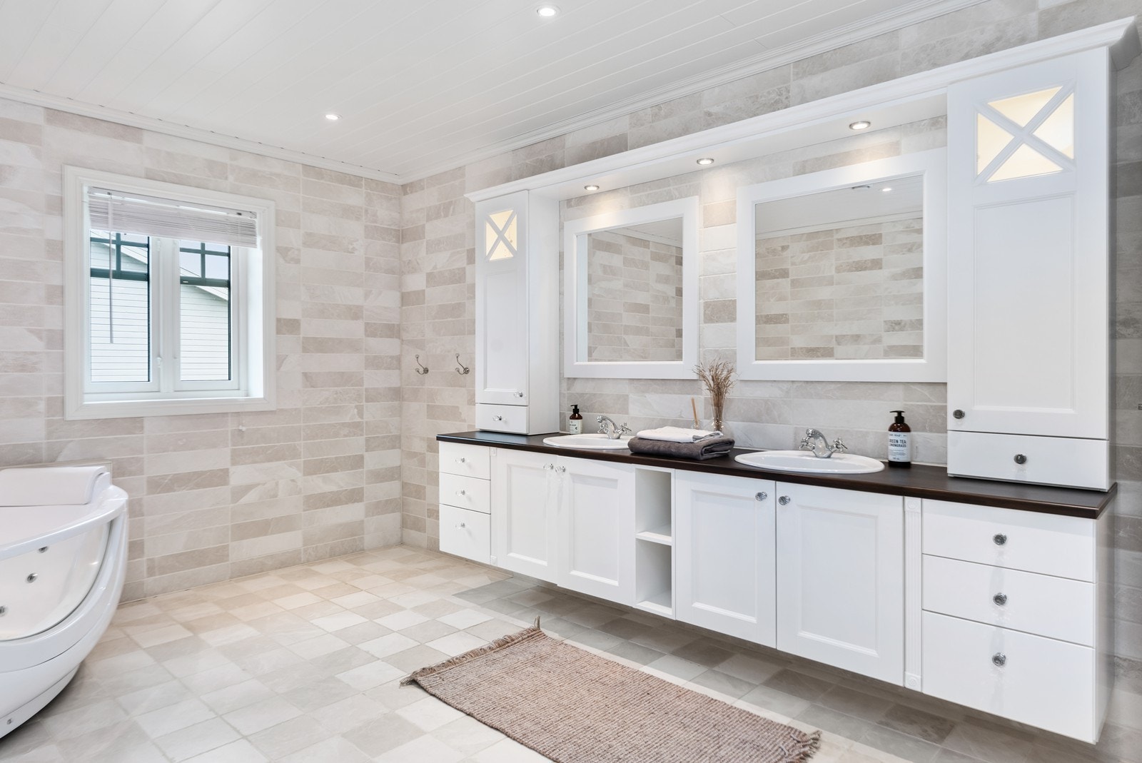 Lekkert bad med marmorfliser, romslig innredning med to servanter, boblebadekar, wc og dusj Galleribilde