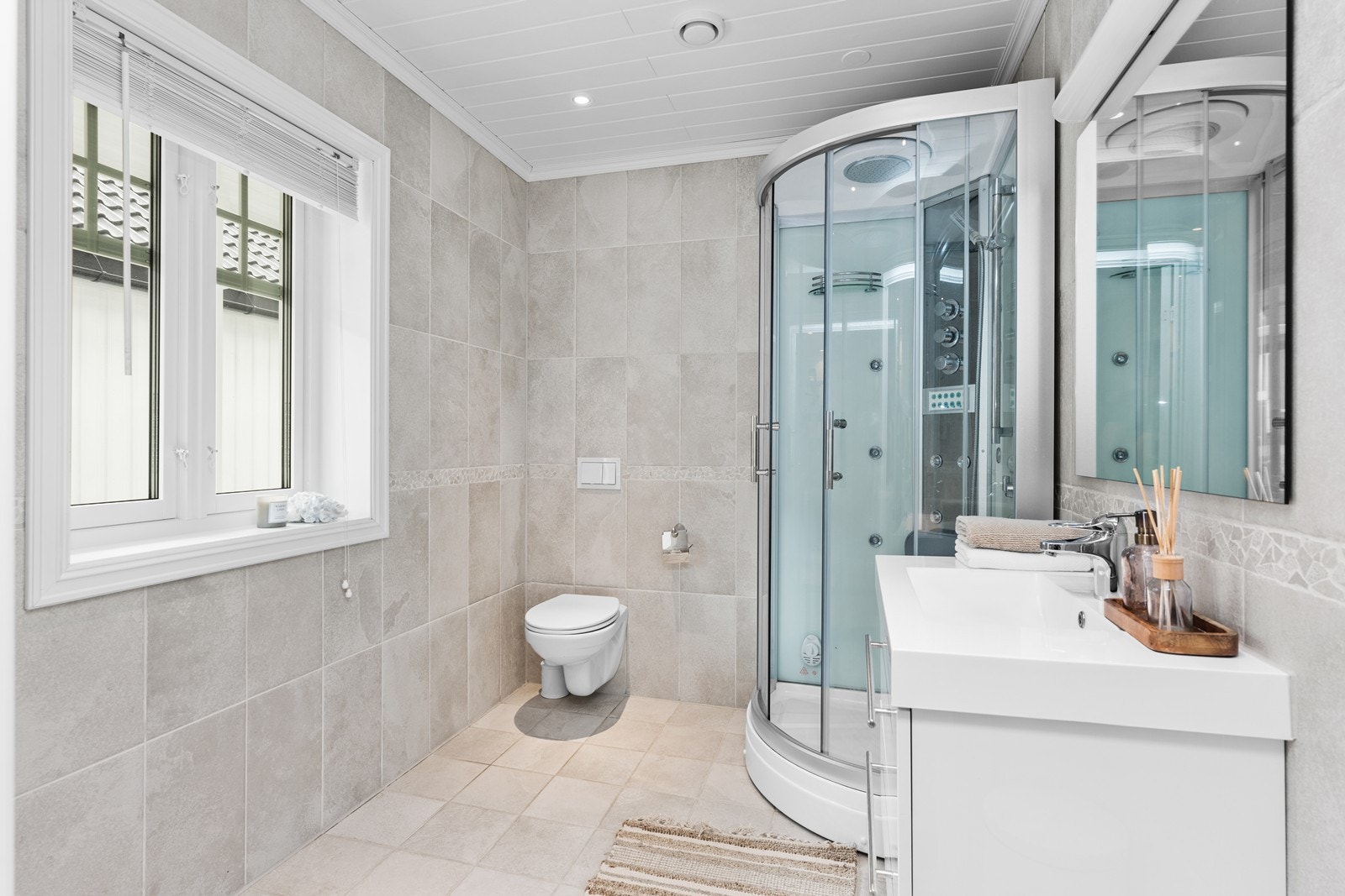 Lyst, flislagt bad med dusjkabinett, vegghengt wc og servant Galleribilde