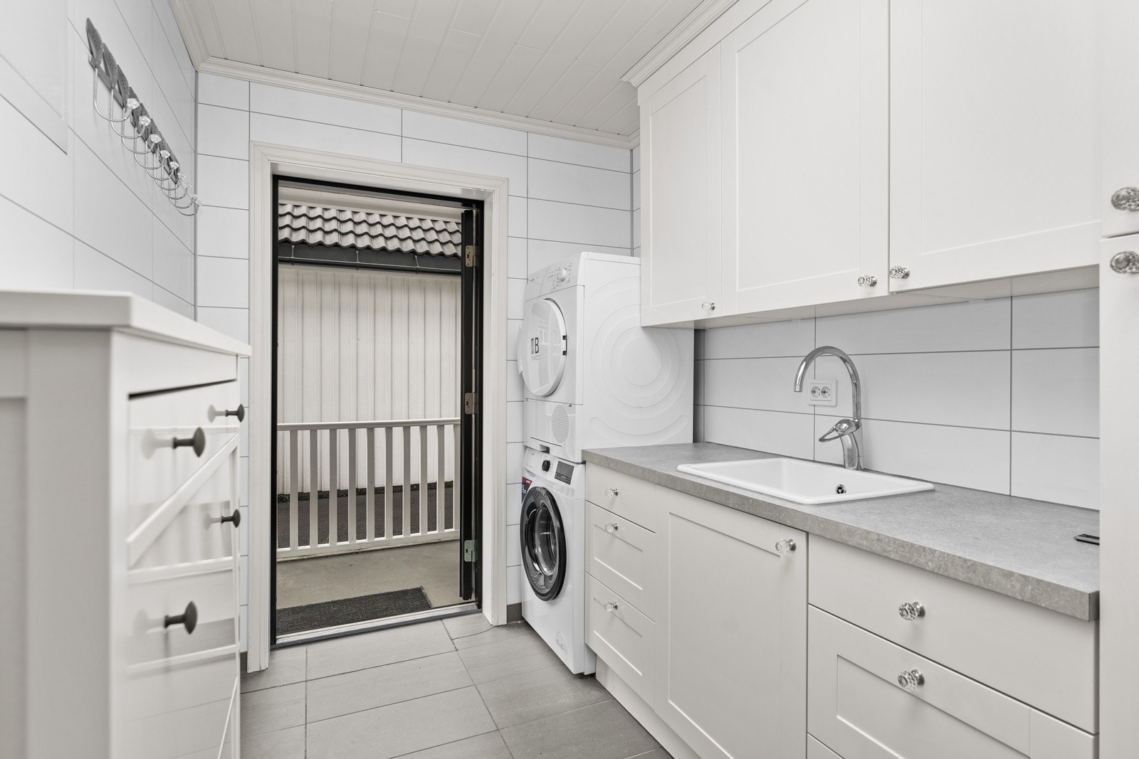 Praktisk vaskerom med flislagt gulv. Innredning fra Strai som har god skap- og benkplass Galleribilde