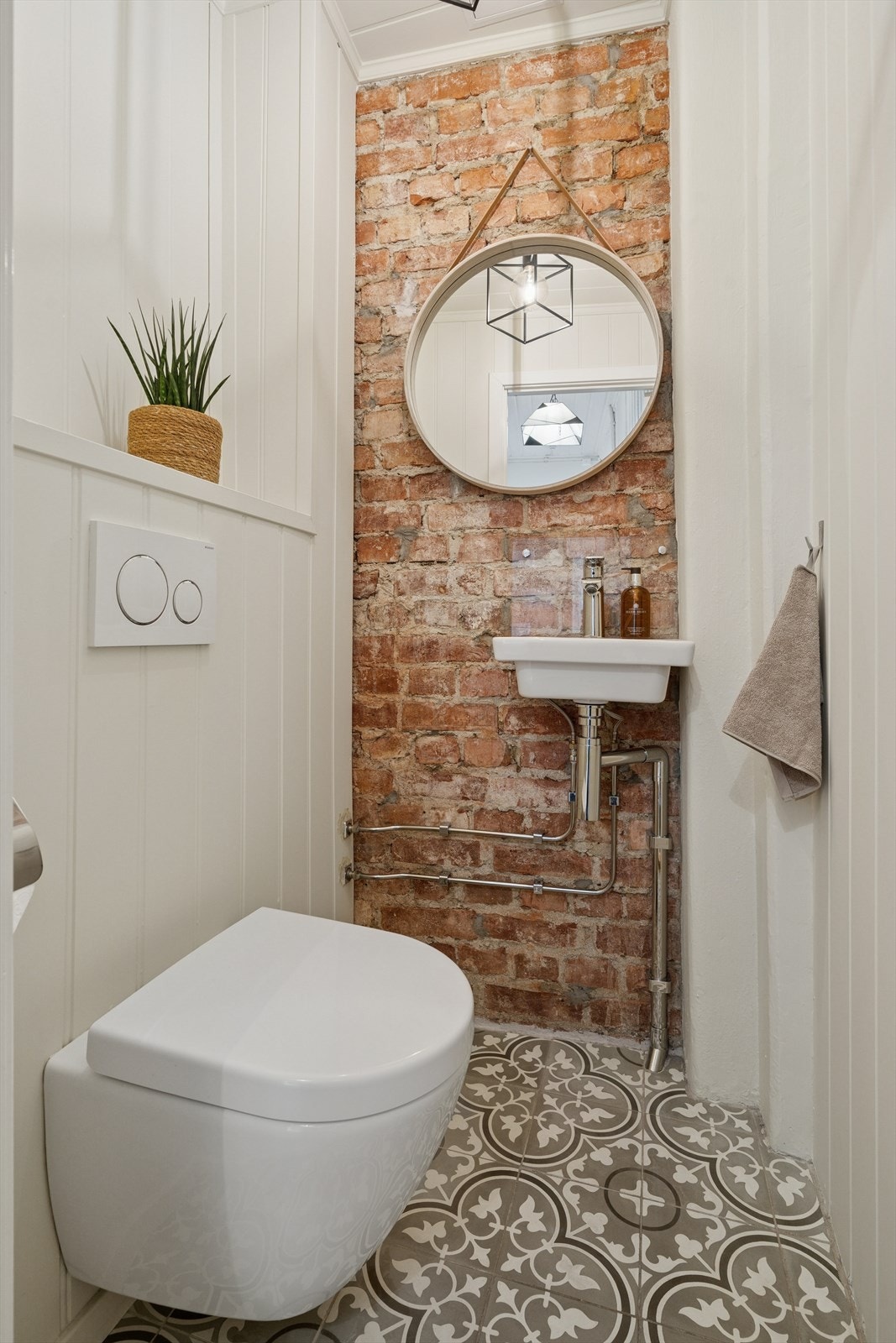 Separat toalett med historiske fliser på gulv og teglestein på vegg. Galleribilde