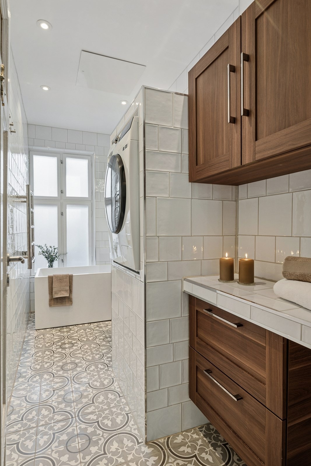 Moderne bad bestående av badekar, opplegg til vaskemaskin, overskap og skuffer samt servant med underskuffer. Galleribilde