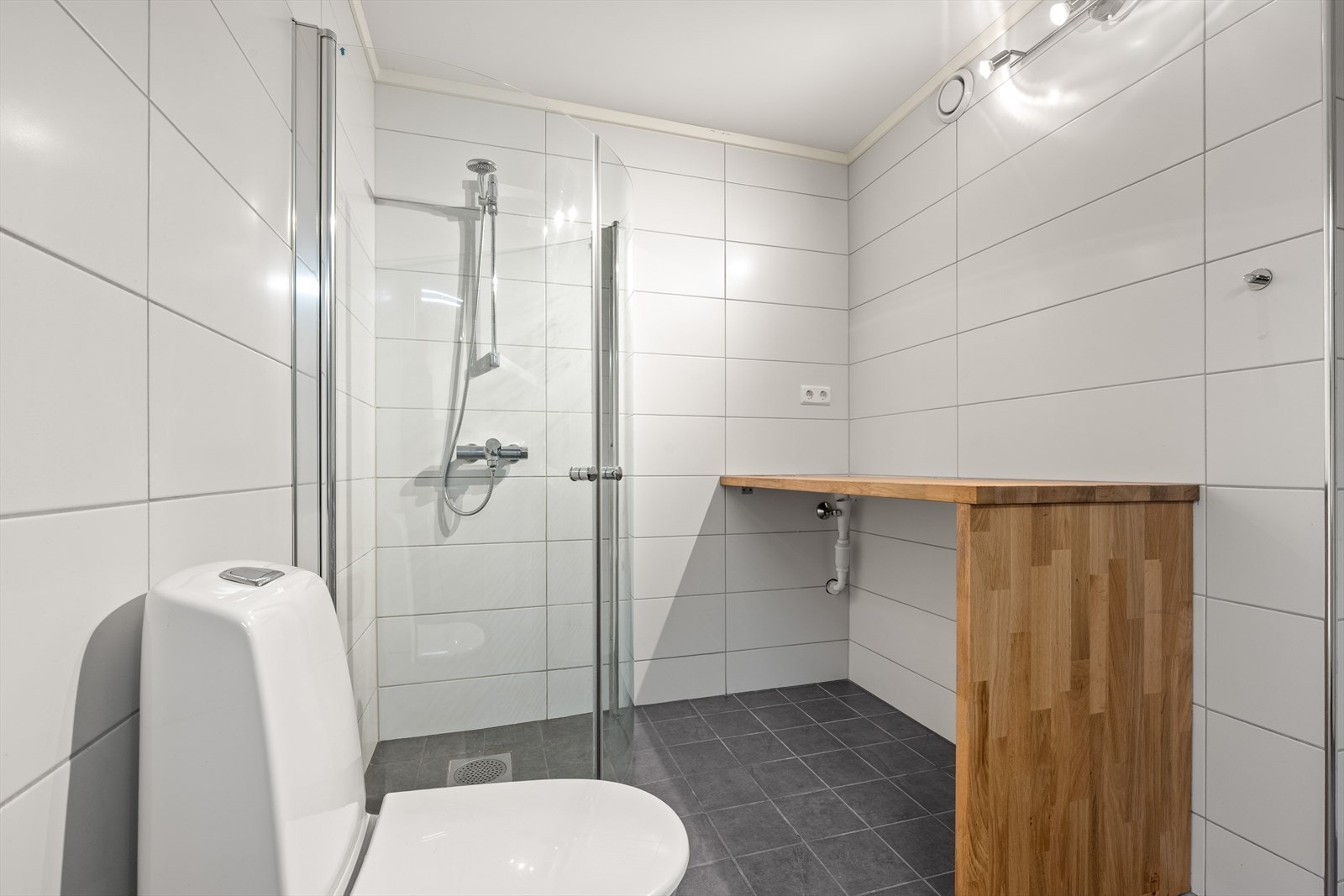 Innredet med servant, dusj med glassdører, toalett og opplegg for vaskemaskin Galleribilde