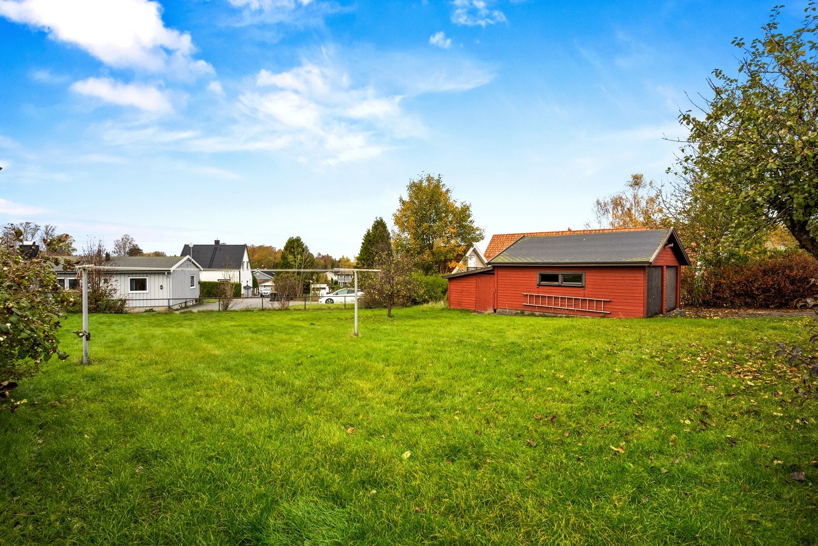 Tomten er svakt skrånende og barnevennlig - og er opparbeidet med gressplen og beplantning Galleribilde