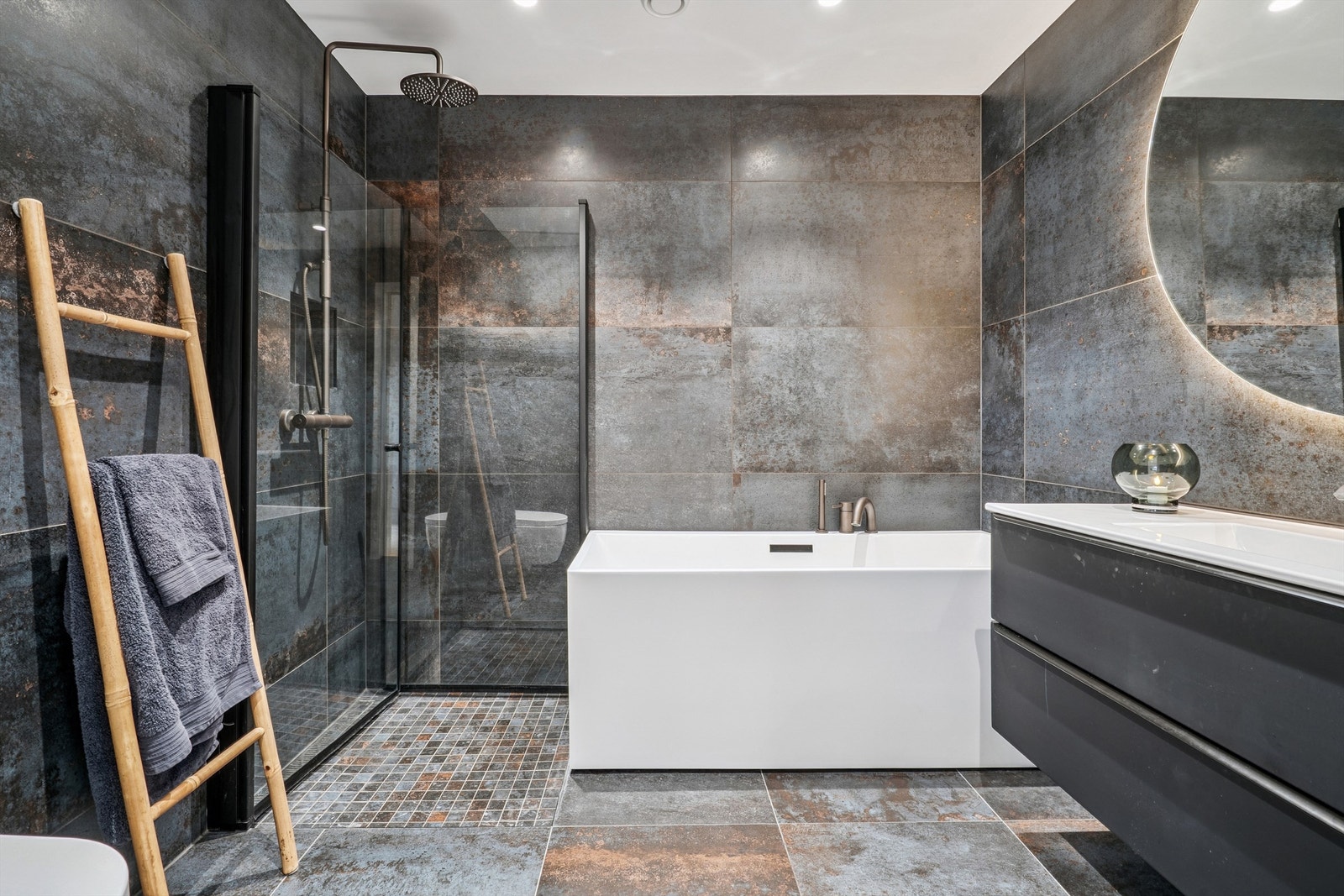 Etasjens hovedbad er elegant utført med store fliser, badekar og separat dusjnisje. Galleribilde