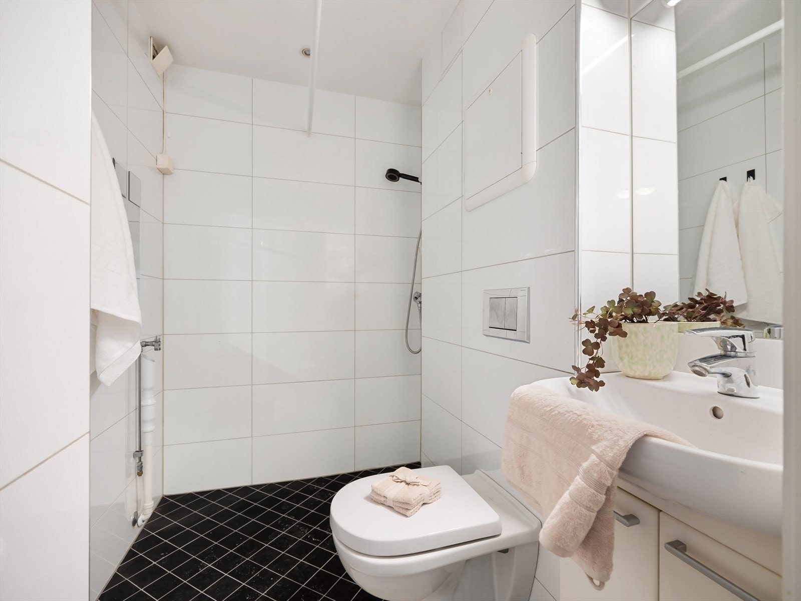 Baderom med dusjhjørne. Vegghengt toalett og opplegg for vaskemaskin / tørketrommel. Galleribilde