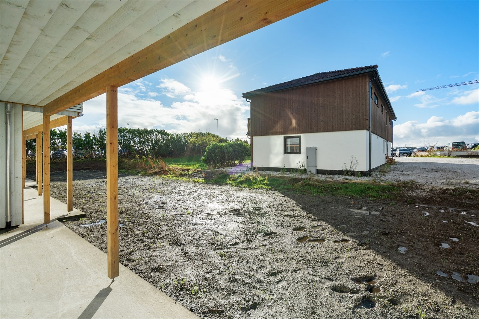 Vestvendt og overbygget betongplatting med utgang til hage med boltreplass til utelek og trampoline Galleribilde