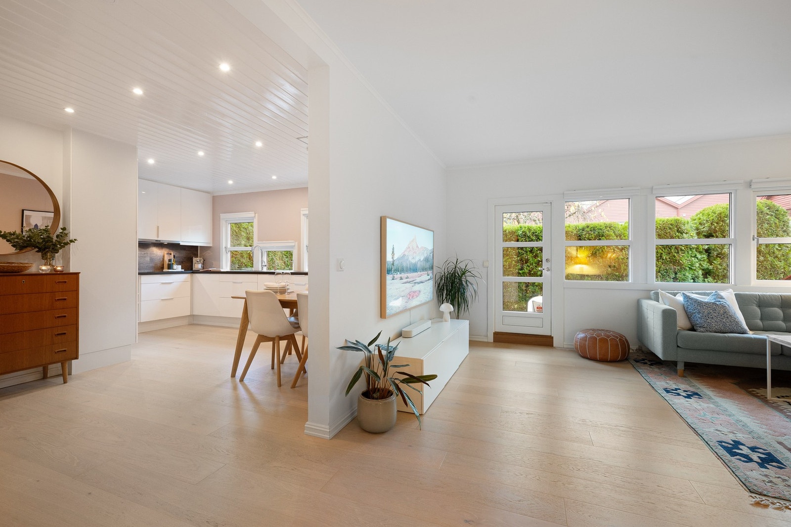 Den åpne løsningen mot kjøkkenet gir en sosial og luftig atmosfære mellom stue og kjøkken, samtidig som en halvvegg skaper en naturlig og praktisk soneinndeling. Galleribilde