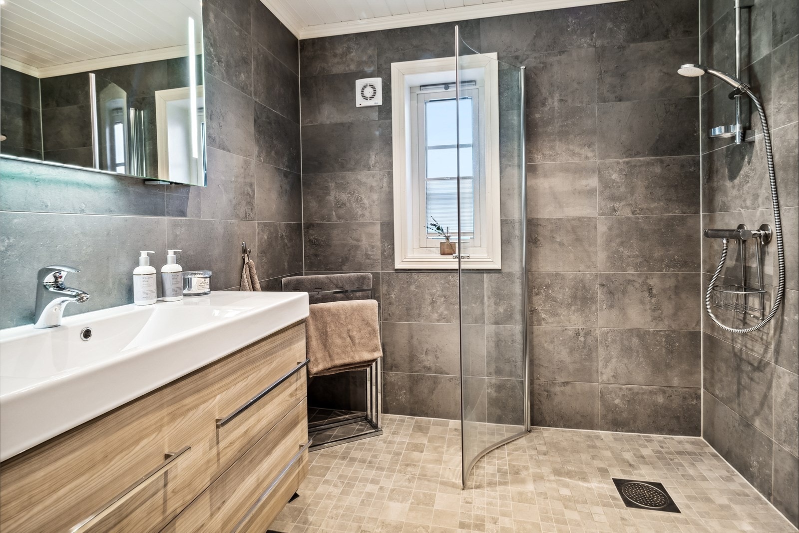 Moderne flislagt bad med gulvvarme, dusjhjørne, vegghengt wc og romslig innredning Galleribilde