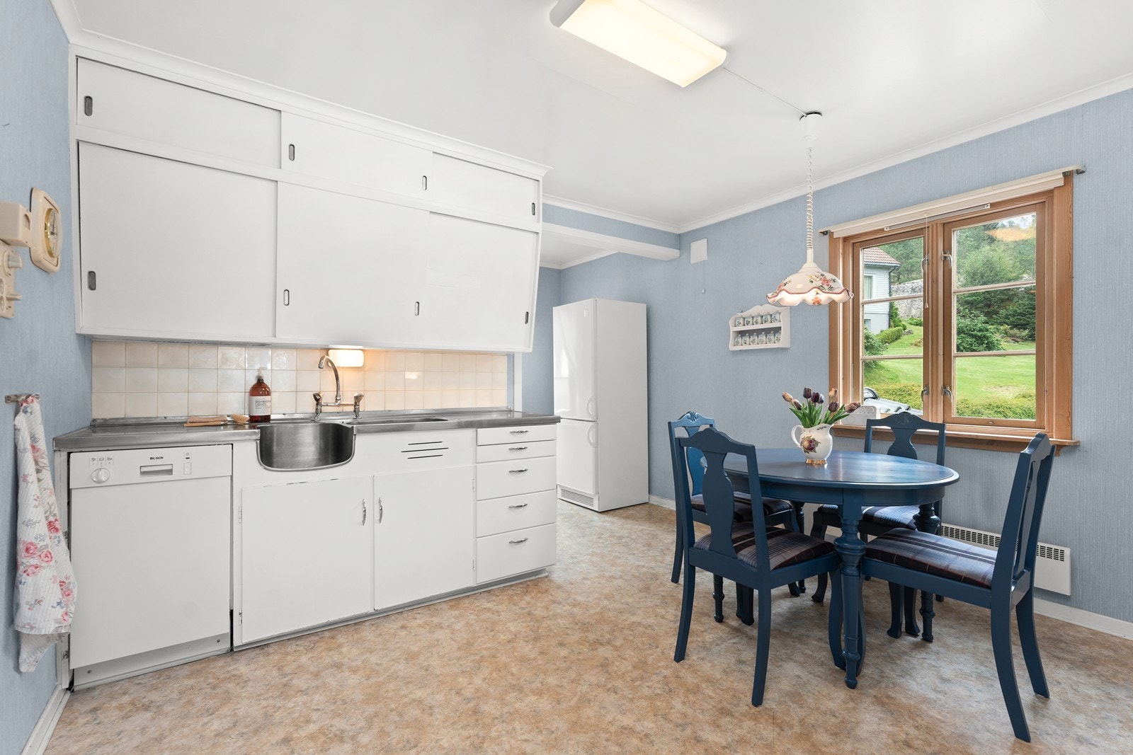 Stort kjøkken med eldre innredning og spisebord. Galleribilde