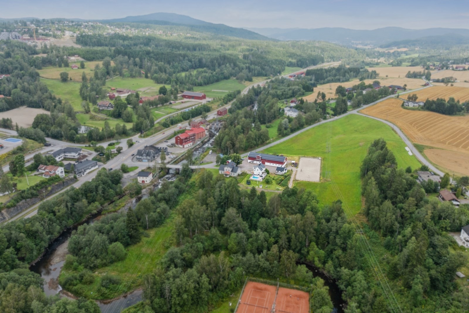 Beite strekker seg fra paddockene som er i nærheten av bassenget og helt ned til elva. Beite består av både gress og skog. Huset til venstre på tunet er ikke en del av salget og følger ikke med. Galleribilde