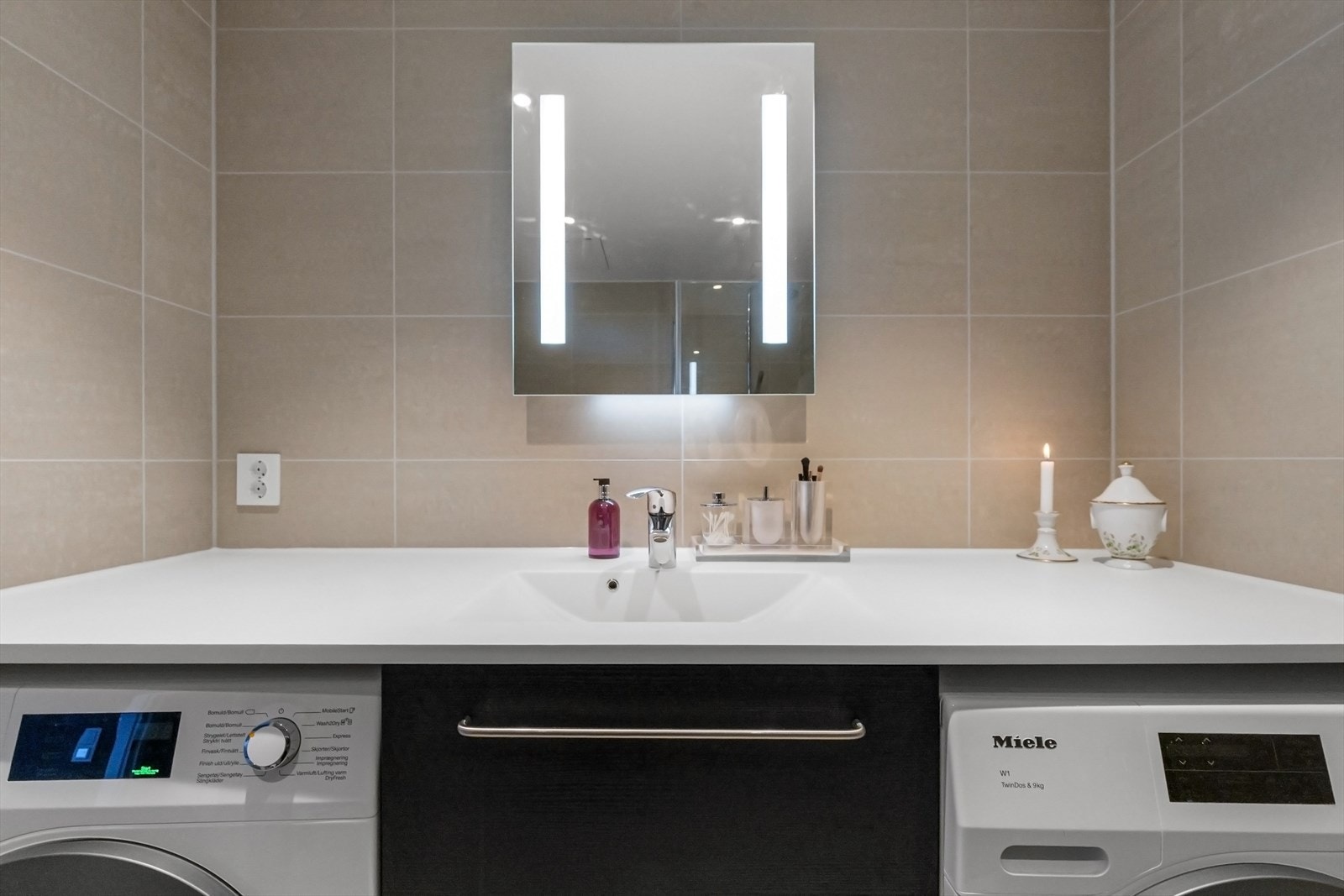 Benkeplate med servant over benkeskap, og speil med belysning over servant. Galleribilde