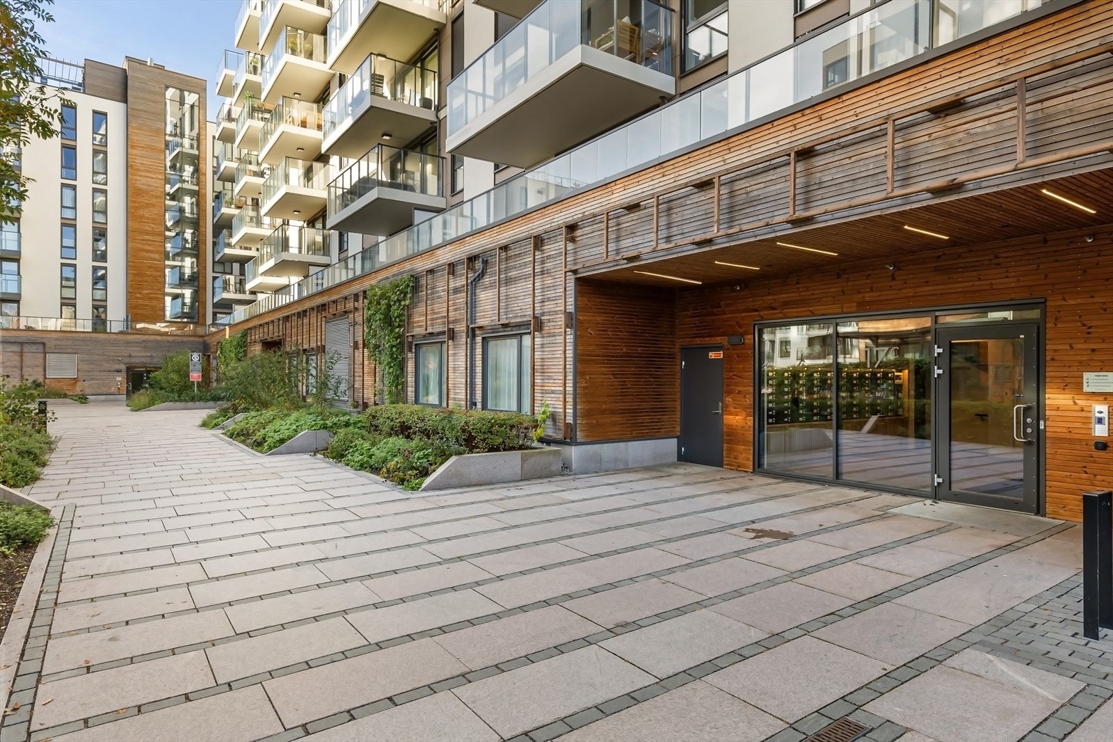 Moderne inngangsparti med grønne omgivelser og gjennomført arkitektur. Galleribilde