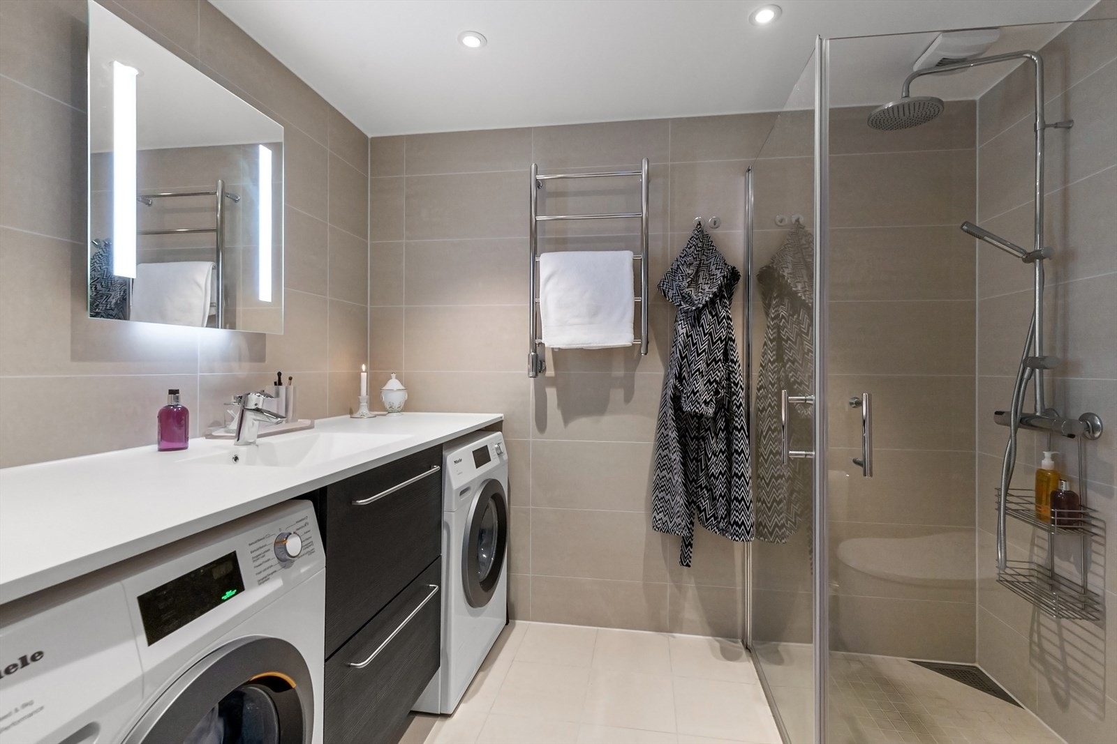 Bad 1 med dusj med innfellbare dører i herdet glass, veggfestet japansk toalett med innebygget sisterne og opplegg for vaskemaskin. Flislagt gulv med varmekabler. Galleribilde