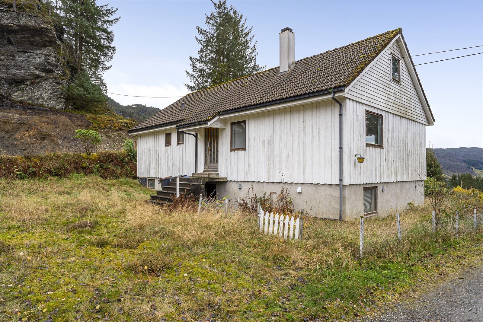 Utvendig er eiendommen er opparbeidet med plen, beplantning og gjerde. Tomta er preget av vedlikeholdsetterslep. Kjøper må påregne vedlikehold og oppgraderinger. Galleribilde