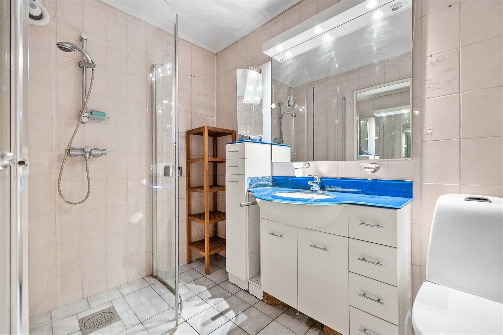 Badet i hybelen har eldre standard, men byr på en praktisk og funksjonell løsning med alt man trenger til daglig bruk. Rommet er innredet med dusjhjørne, servantskap med speil, klosett og oppbevaringsskap. Galleribilde