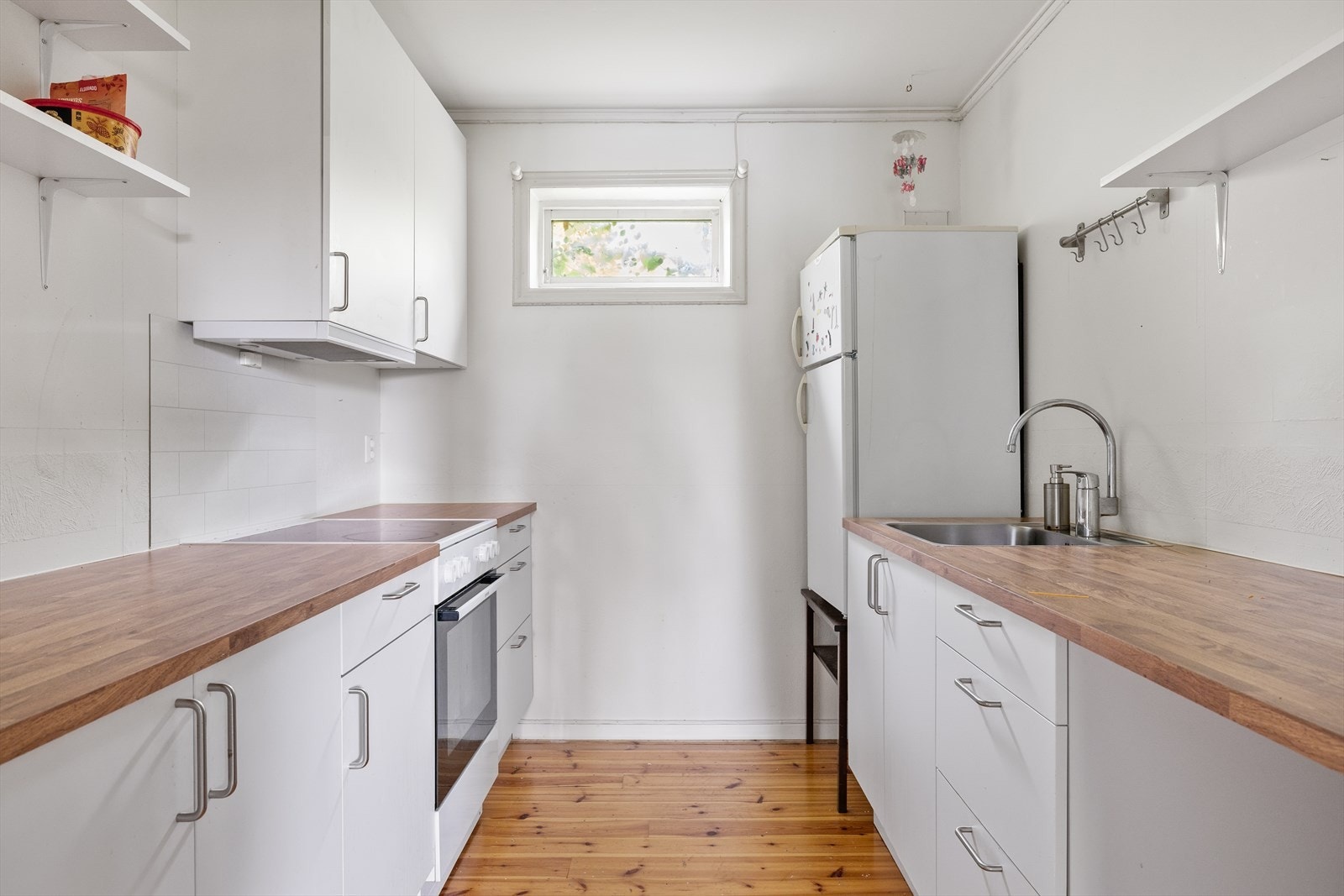 Kjøkkenet i hybelen er funksjonelt og lyst, med innredning med glatte fronter og benkeplate i laminat med nedfelt oppvaskkum. Her er det lagt vekt på praktiske løsninger og god utnyttelse av plassen, perfekt for en mindre husholdning. Galleribilde