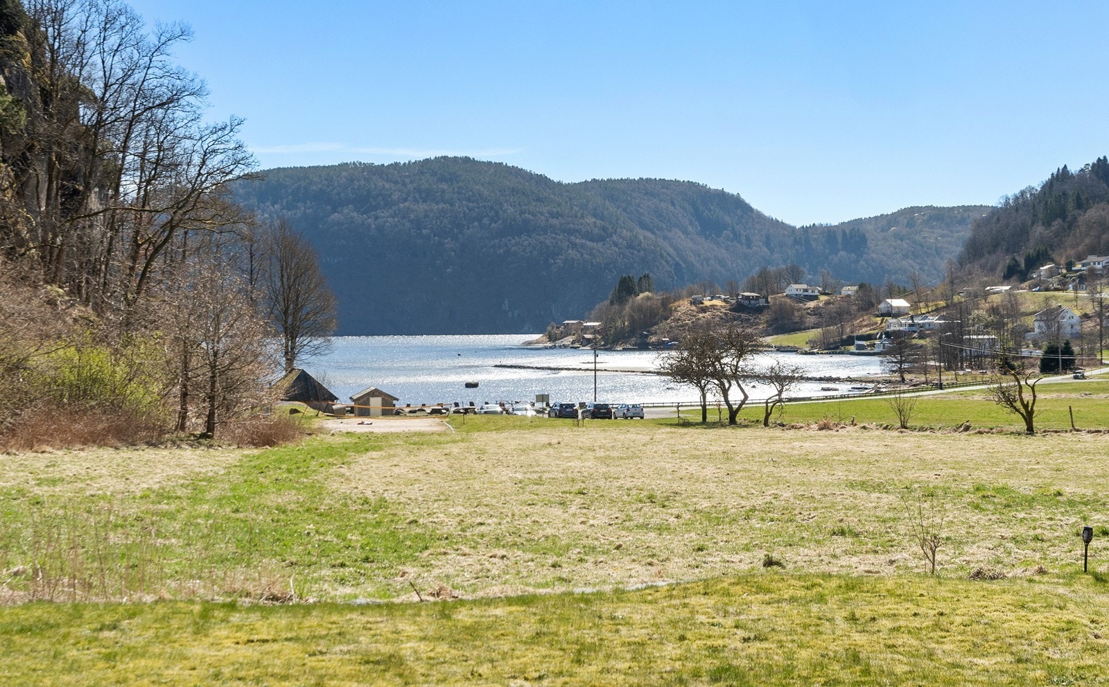 Utsikt ned mot sjøkanten hvor det er et populært friluftsområde med sandstrand. Galleribilde