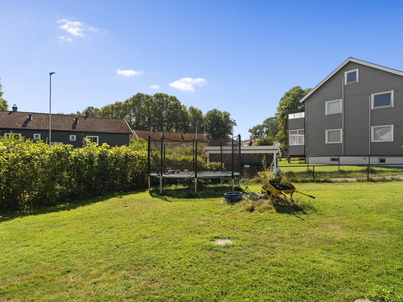 Romslig og solrik felles hage som er delvis innhegnet med gjerde og hekk. Galleribilde