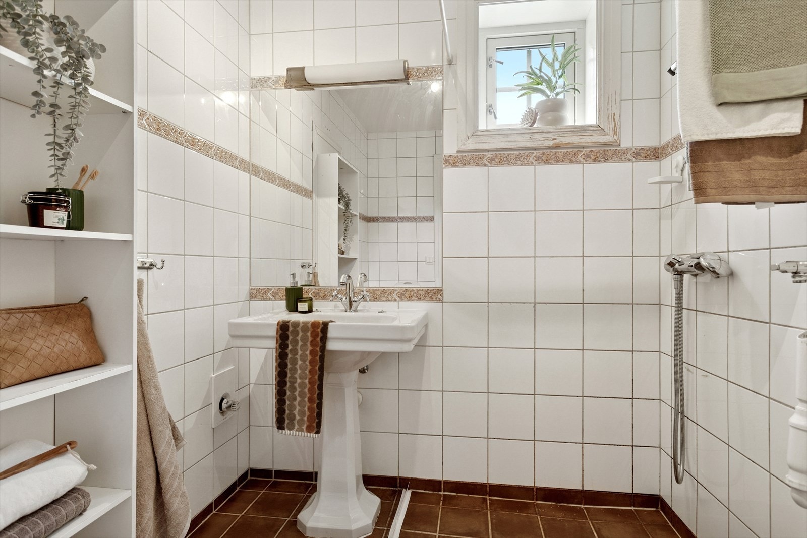 Badet har åpen dusjsone, servant med lyssatt speil over, gulvmontert toalett samt opplegg for vaskemaskin. Galleribilde