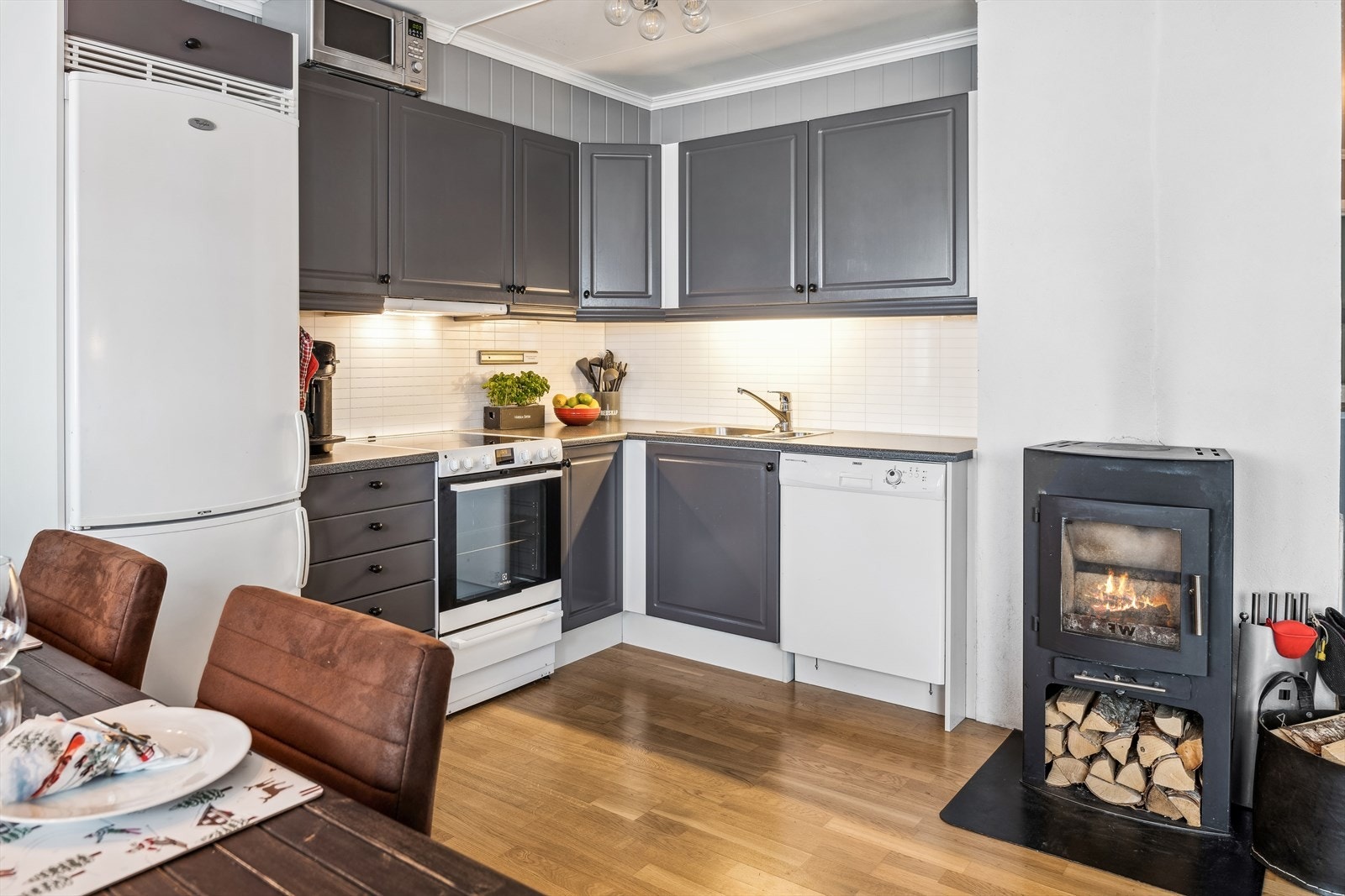 Kjøkkenet har hvitevarer med komfyr, oppvaskmaskin og kombiskap med kjøl/frys montert i kjøkkennisjer. Ventilator over komfyr. Galleribilde