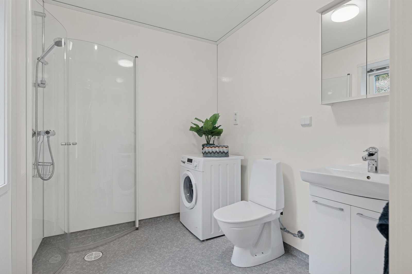 Flott baderom i 1. etasje. Innredet med praktisk plassbesparende dusjvegger, servant med skaper, gulvstående toalett og god plass til vaskemaskin. Galleribilde