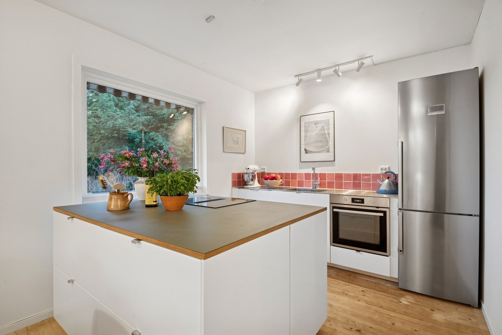 Pent kjøkken fra 2023, hvit innredning med slette fronter og stål/linoleum benkeplate med støpt oppvaskkum. Galleribilde